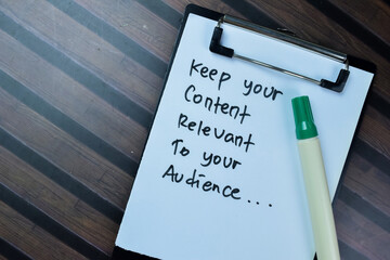 Concept of Keep Your Content Relevant To Your Audience write on paperwork isolated on Wooden Table.