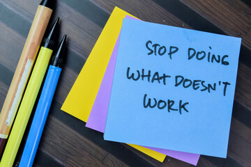 Concept of Stop Doing What Doesn't Work write on sticky notes isolated on Wooden Table.