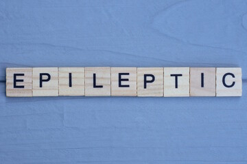text the word epileptic from brown wooden small letters with black font on an gray table