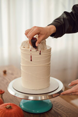 Сonfectioner woman decorates a cake with blood for Halloween. Cake idea
