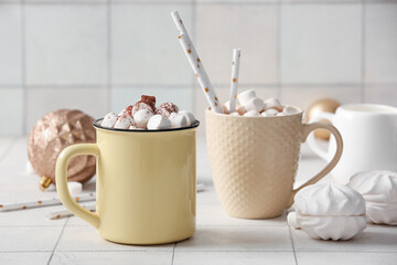 Cups of hot cocoa with marshmallows on white tile background