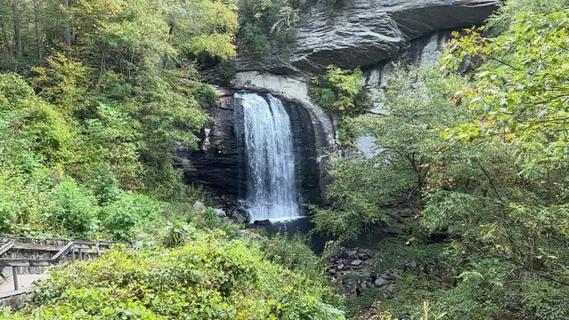 Beautiful wide waterfall with white water cascading in slow motion over darkened rocks in the mountains