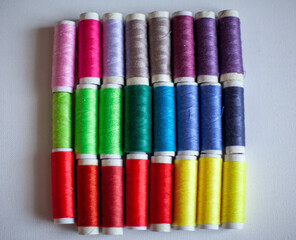 A set of colourful spools of thread placed in three rows