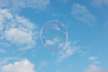 Big soap bubbles fly through the air in front of a blue sky