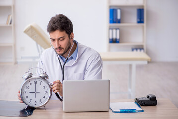 Young male doctor in time management concept