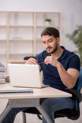 Young male employee sitting at workplace