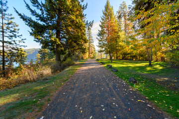 Paved path along the lakefront walking centennial trail at the Coeur d'Alene Parkway State Park at Higgens Point on the lake at autumn, in Coeur d'Alene, Idaho USA.