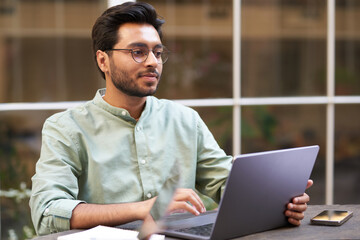 Stylish businessman sitting in modern coworking and working on laptop. High quality photo