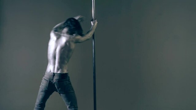 Strip dancer. Fit slim muscular man on pole dance. Pole dancer on pylon. Shirtless strong sexy man dancing. Male flexibility, and grace. Guy performing trick on pole. Male athlete doing acrobatic