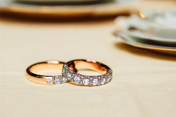 Wedding rings on a table in a wedding related environment symbolizing two people getting into a union. Generated by AI.
