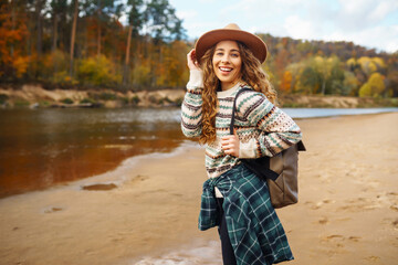 Beautiful woman traveler enjoying autumn hiking along the river. A traveler walks in the autumn forest, enjoying the weather. Active lifestyle.