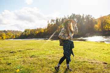 Beautiful woman traveler enjoying autumn hiking along the river. A traveler walks in the autumn forest, enjoying the weather. Active lifestyle.