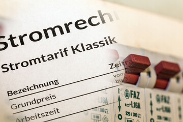 Symbolbild Stromkosten: Nahaufnahme einer Stromrechnung vor einem Verteilerkasten