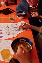 Hand of young businesswoman with pen pointing at financial document with graphic data while...