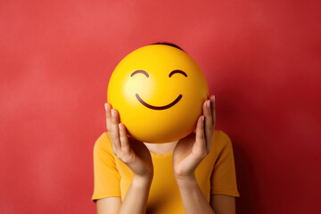 Woman in yellow t-shirt holds huge big smiling face in her hands instead of head. Positive morning emotion, motivation, self love, mental health, optimism, positive thinking