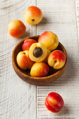 Juicy ripe smooth apricots in a wooden plate on a wooden background. Fruit