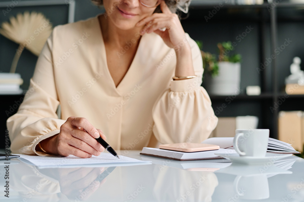 Poster Hand of mature female accountant pointing at financial document or business contract while reading its points and checking information