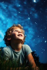 A happy amazed kid is sitting on the grass and watching the sky full of stars