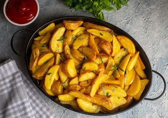 Roasted potato wedges with herbs and sea salt on plate, top view (Turkish name; elma dilim patates)