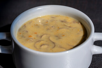 White bowl of delicious homemade cream of mushroom soup on table, closeup