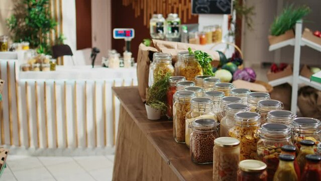 Additives free pantry staples on eco friendly zero waste supermarket shelves. Organic food in biodegradable reusable glass jars on display in empty local neighborhood grocery store
