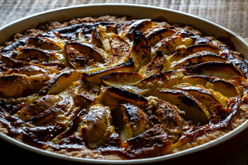 Apple pie in a ceramic baking dish on a wooden table. Homemade apple pie. Closeup