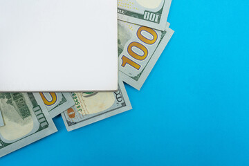 Book Mockup with Many Bills Inside, Financial Education Concept with Copy Space on a Blue Background