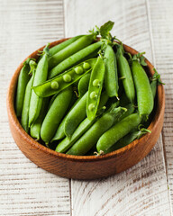 Young juicy green peas in a pod on a wooden plate. healthy food, vegetables.