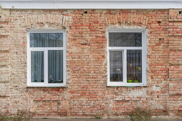 Fototapeta na wymiar White three-section PVC windows. Brick old wall without plaster.