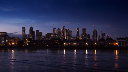 Fototapeta premium Night view on Isle of Dogs and Canary Wharf from the bank of the Thames river, Grivich district. 16x9 photo