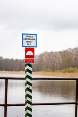 Information board in Polish "Punkt czerpania wody, przeciwpożarowe stanowisko czerpania wody", forest, cloudy day (selective focus), translation: water drawing point, fire protection stand