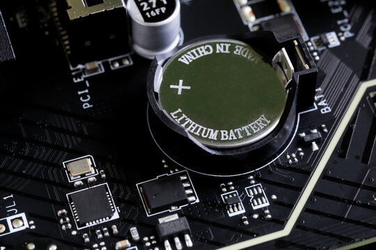 A made-in-China lithium battery installed in a modern computer's motherboard to power CMOS memory. Photo. Macro. Selective focus.