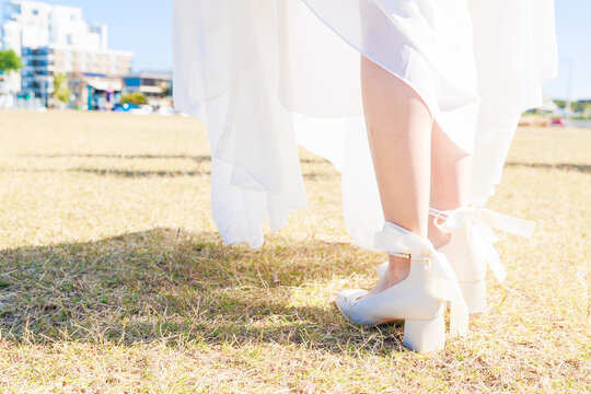 晴れた日に芝生を歩く新婦の足元