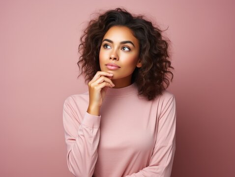 A young woman in a pink top looks off to the side, her curly hair framing her face beautifully against a pink background.