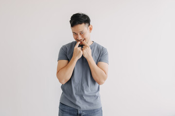 Shy and embarrassment funny asian man in blue t-shirt isolated on white wall.