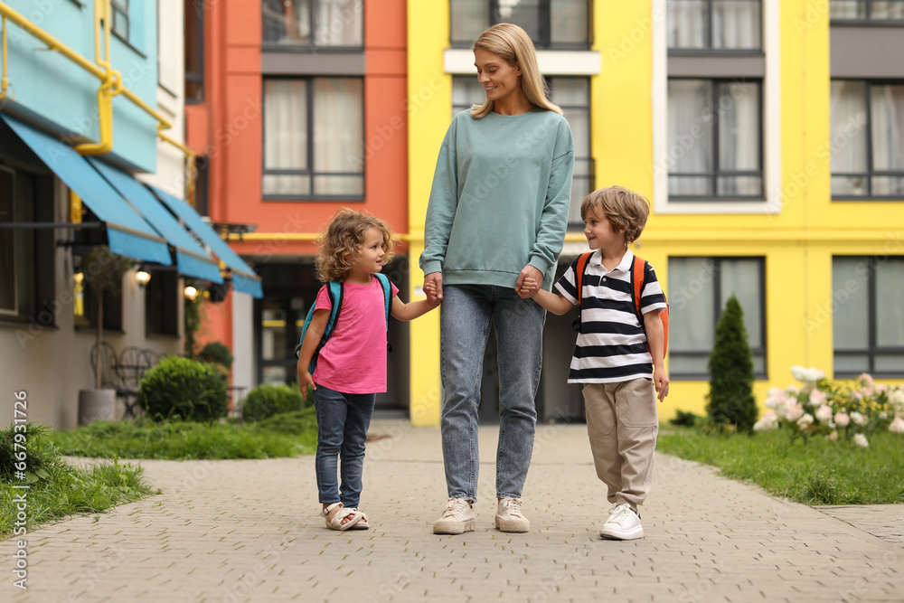 Sticker Woman and her children on their way to kindergarten outdoors, low angle view