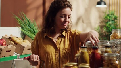 Vegan woman in specialty zero waste supermarket tasting pantry items before adding them to shopping basket. Client in local shop trying out food to determine if it's toxins free before buying