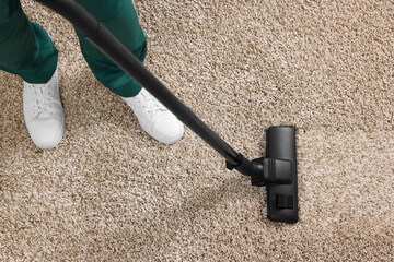 Dry cleaner's employee hoovering carpet with vacuum cleaner, above view
