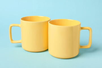 Two yellow ceramic mugs on light blue background