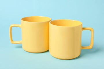 Two yellow ceramic mugs on light blue background