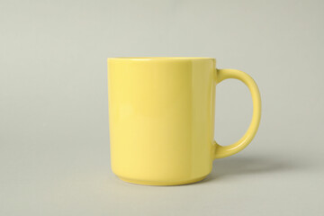 One yellow ceramic mug on light grey background
