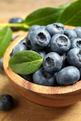 Bowl of tasty fresh blueberries on wooden table, closeup