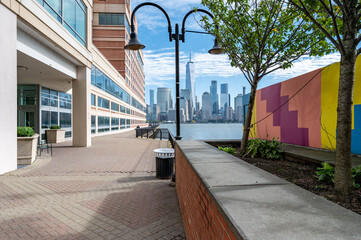 A stunning view of New York's iconic skyline complemented by the picturesque sights of Jersey City Harbor. Perfect for urban and waterfront showcases.