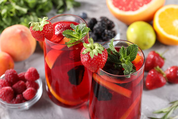 Delicious refreshing sangria with fresh fruits and berries on light grey table, closeup