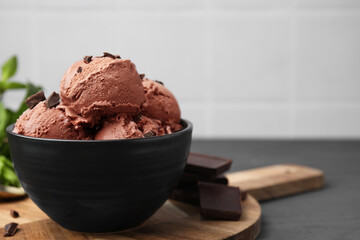 Bowl with tasty chocolate ice cream on grey wooden table, closeup. Space for text