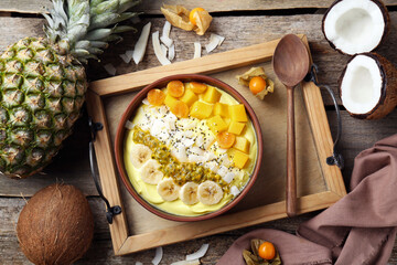 Tasty smoothie bowl with fresh fruits served on wooden table, flat lay