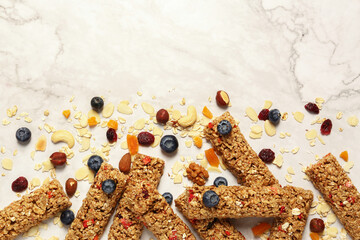 Tasty granola bars and ingredients on white marble table, flat lay. Space for text
