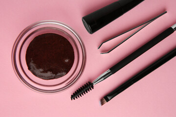 Flat lay composition with eyebrow henna and professional tools on pink background