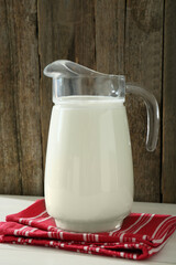 Jug of fresh milk on white wooden table
