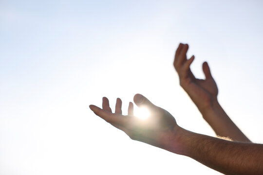 Feeling freedom. Man reaching for sky on sunny day, closeup of hands